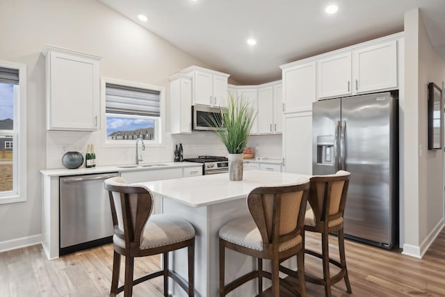 6749 168th Ln N, Ramsey, MN 55303 - kitchen with appliances with stainless steel finishes, a sink, tasteful backsplash, a breakfast bar area, and white cabinetry