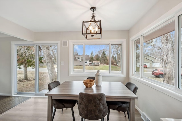 761 Labore Rd, Little Canada, MN 55117 - dining area featuring healthy amount of natural light, a chandelier, wood finished floors, and baseboards