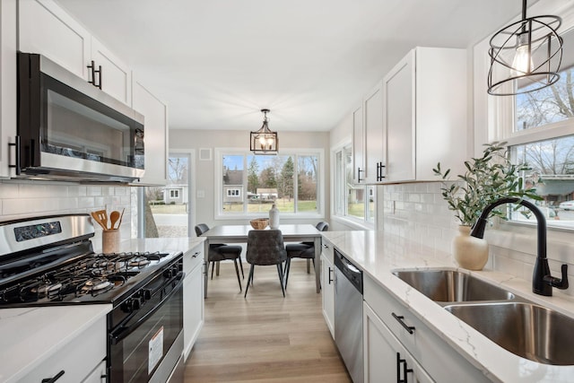 761 Labore Rd, Little Canada, MN 55117 - kitchen featuring appliances with stainless steel finishes, a sink, a chandelier, light wood-style flooring, and white cabinetry