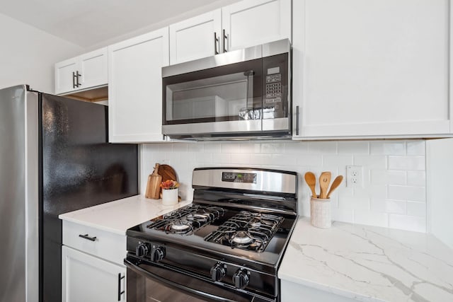 761 Labore Rd, Little Canada, MN 55117 - kitchen featuring stainless steel microwave, black range with gas stovetop, white cabinetry, freestanding refrigerator, and decorative backsplash