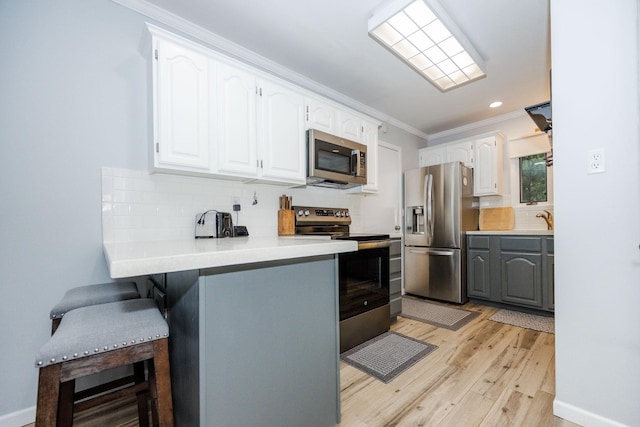30202 Shady Ln, Detroit Lakes, MN 56501 - kitchen featuring appliances with stainless steel finishes, ornamental molding, white cabinetry, light wood-style flooring, and tasteful backsplash