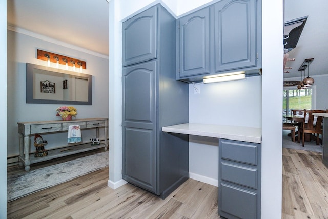 30202 Shady Ln, Detroit Lakes, MN 56501 - kitchen with blue cabinets, light wood-type flooring, light countertops, crown molding, and baseboards