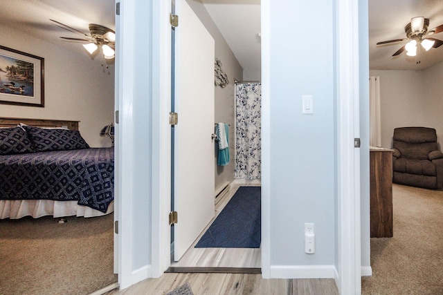 30202 Shady Ln, Detroit Lakes, MN 56501 - bedroom with baseboard heating, light colored carpet, a ceiling fan, and light wood-type flooring