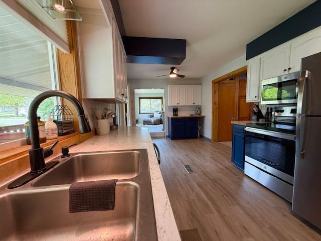 725 8th St NE, Staples, MN 56479 - kitchen featuring a sink, stainless steel appliances, blue cabinetry, white cabinets, and light countertops