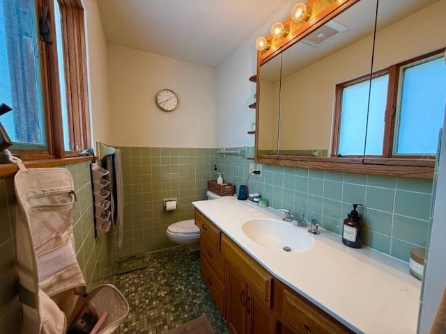 725 8th St NE, Staples, MN 56479 - bathroom featuring tile walls, toilet, vanity, a wainscoted wall, and tile patterned flooring