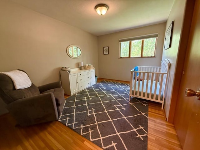 725 8th St NE, Staples, MN 56479 - bedroom with wood finished floors, a crib, and baseboards