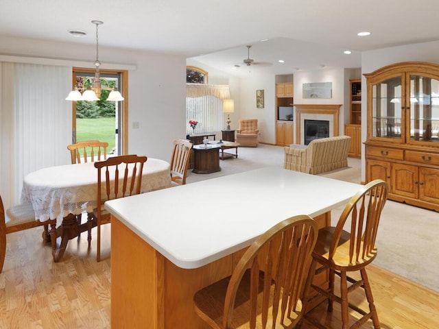 1232 Cypress Dr W, Annandale, MN 55302 - kitchen featuring light wood-type flooring, a kitchen island, a kitchen bar, a glass covered fireplace, and decorative light fixtures