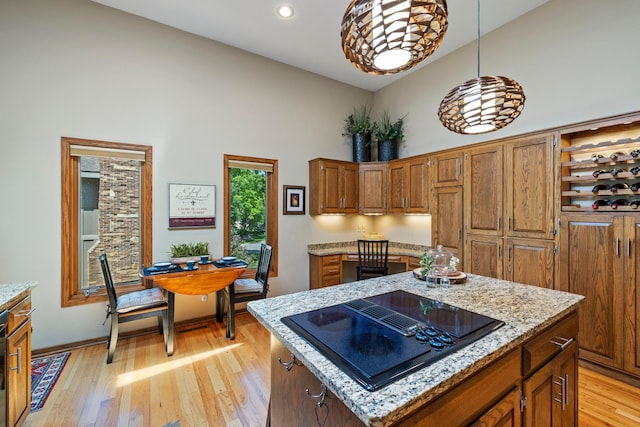 9378 Olympia Dr, Eden Prairie, MN 55347 - kitchen with black electric stovetop, a high ceiling, brown cabinets, light wood finished floors, and a center island