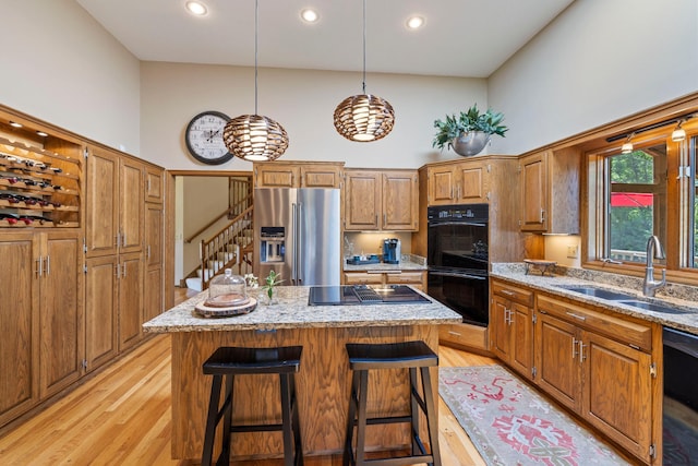 9378 Olympia Dr, Eden Prairie, MN 55347 - kitchen featuring black appliances, a high ceiling, a kitchen island, brown cabinetry, and light wood-style flooring
