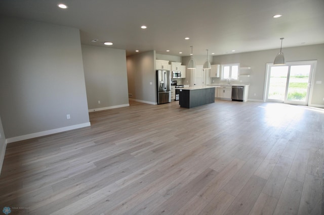 unfurnished living room with a sink, light wood-type flooring, baseboards, and recessed lighting