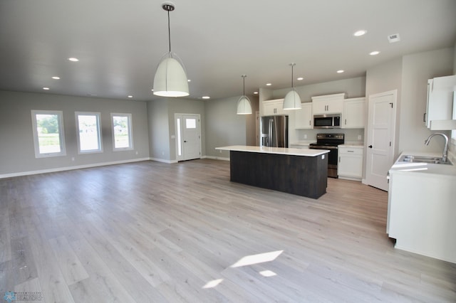 kitchen with stainless steel appliances, a sink, a center island, recessed lighting, and light countertops