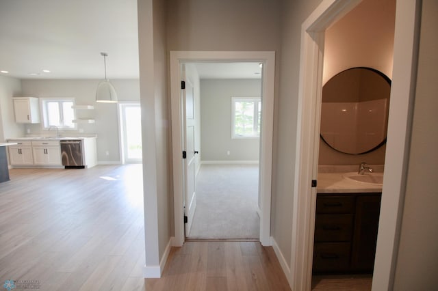 hall featuring a sink, light wood-type flooring, plenty of natural light, and recessed lighting