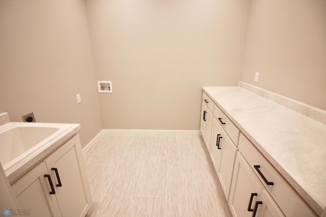 washroom featuring hookup for a washing machine, baseboards, and a sink