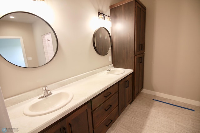 full bath with double vanity and baseboards