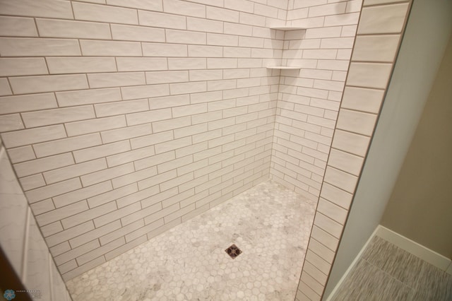 bathroom featuring tiled shower, tile patterned floors, and baseboards
