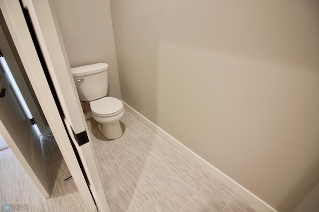 bathroom with toilet, baseboards, and tile patterned floors