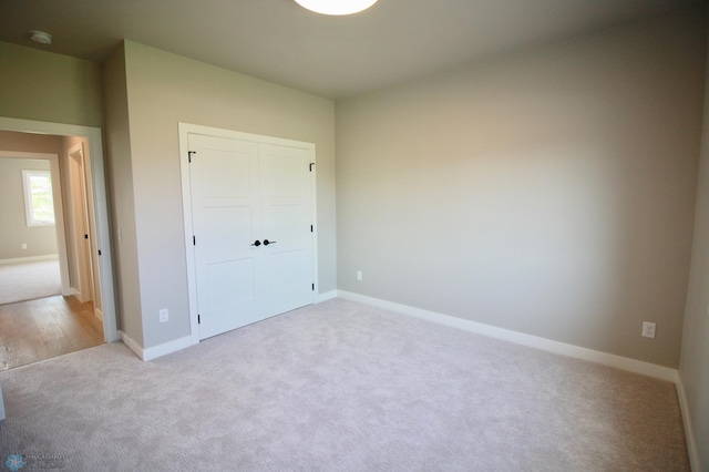 unfurnished bedroom with carpet floors, a closet, and baseboards