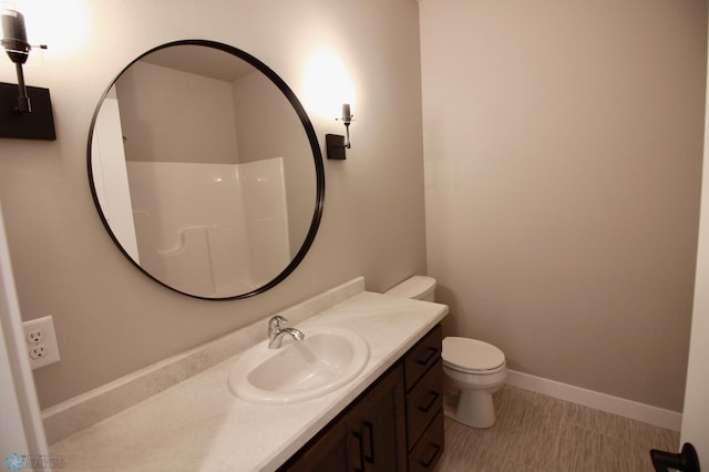 bathroom featuring toilet, vanity, and baseboards