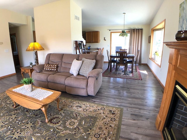 living area featuring dark wood-style floors, baseboards, and lofted ceiling
