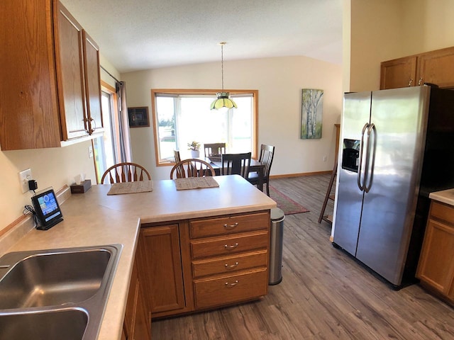 kitchen with stainless steel refrigerator with ice dispenser, lofted ceiling, brown cabinetry, a sink, and dark wood finished floors