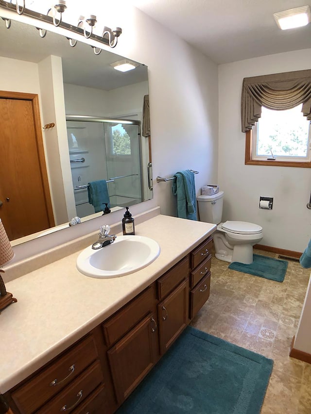 full bathroom featuring a shower stall, vanity, toilet, and baseboards