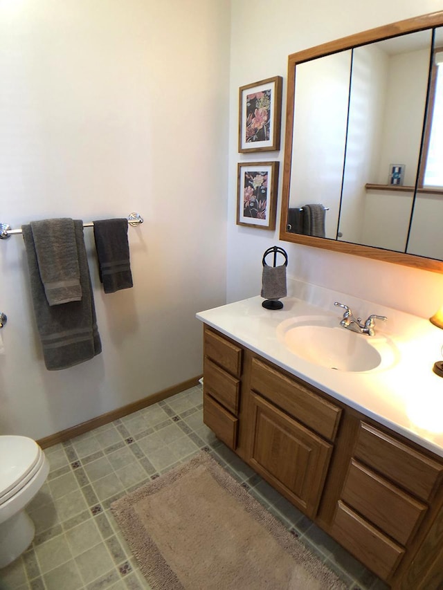 half bath featuring vanity, toilet, and baseboards