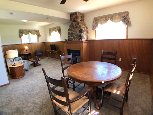 carpeted dining room with a wainscoted wall, wooden walls, and a glass covered fireplace