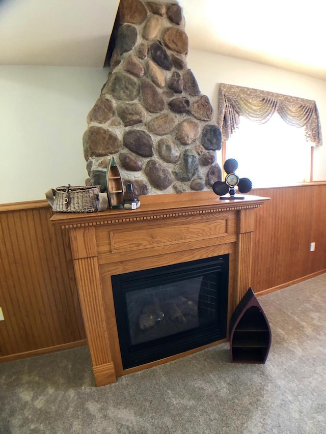detailed view of a wainscoted wall, a fireplace, carpet floors, and wood walls