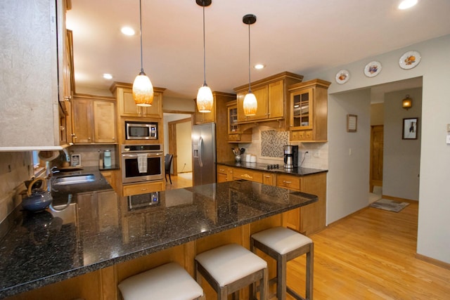 196 Mary Cir, North Mankato, MN 56003 - kitchen with appliances with stainless steel finishes, a peninsula, brown cabinetry, light wood-style flooring, and backsplash