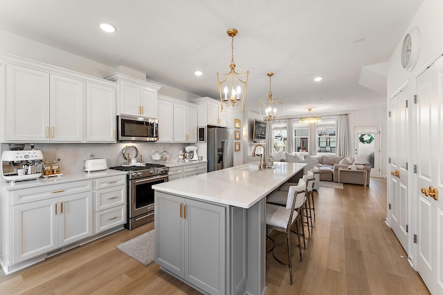 870 Mount Curve Blvd Unit F, Saint Paul, MN 55116 - kitchen featuring stainless steel appliances, a sink, a spacious island, a chandelier, and white cabinetry