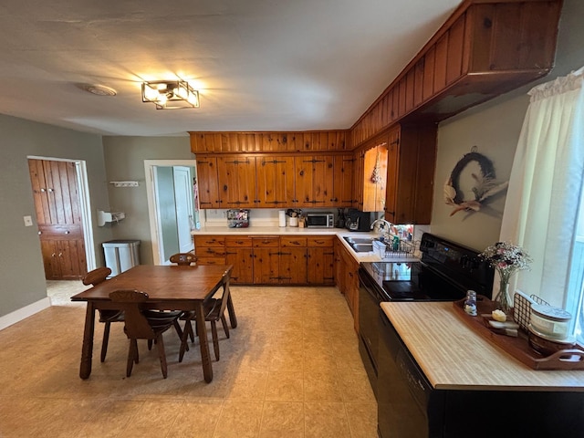 2428 14th Ave E, North Saint Paul, MN 55109 - kitchen with black range with electric stovetop, stainless steel microwave, brown cabinets, light countertops, and light flooring