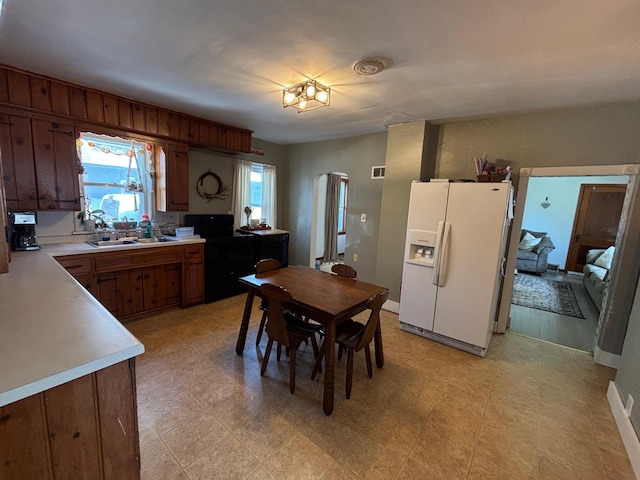 2428 14th Ave E, North Saint Paul, MN 55109 - kitchen featuring white refrigerator with ice dispenser, light countertops, washer / clothes dryer, a sink, and arched walkways