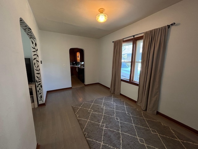 2428 14th Ave E, North Saint Paul, MN 55109 - spare room featuring arched walkways, dark wood-style flooring, and baseboards