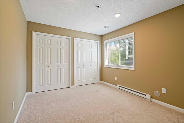 5901 106th Ave N, Brooklyn Park, MN 55443 - unfurnished bedroom featuring a baseboard heating unit, multiple closets, carpet flooring, and a textured ceiling