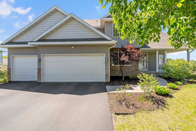 5901 106th Ave N, Brooklyn Park, MN 55443 - view of front of home with driveway, an attached garage, stone siding, covered porch, and roof with shingles