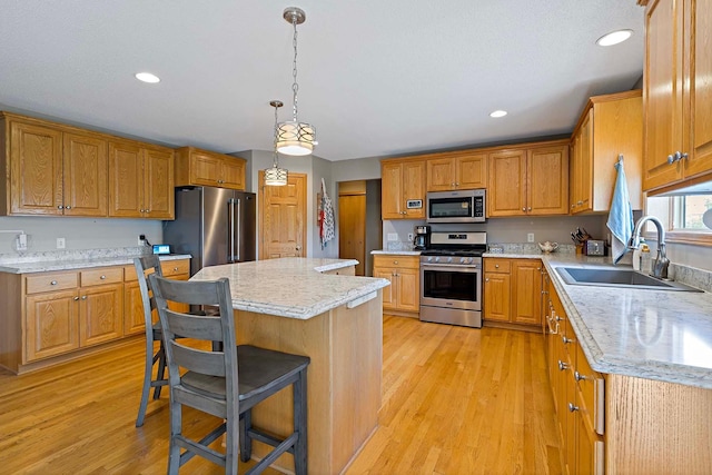 5901 106th Ave N, Brooklyn Park, MN 55443 - kitchen with appliances with stainless steel finishes, a kitchen island, light wood-style floors, a breakfast bar, and recessed lighting