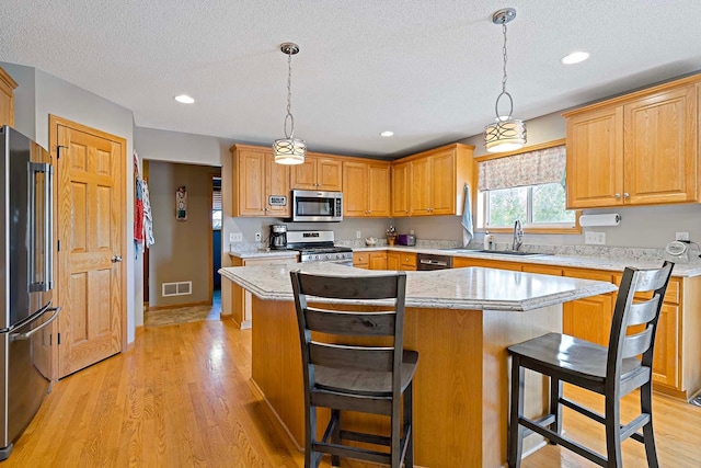 5901 106th Ave N, Brooklyn Park, MN 55443 - kitchen with stainless steel appliances, a textured ceiling, a center island, a breakfast bar, and light wood-type flooring