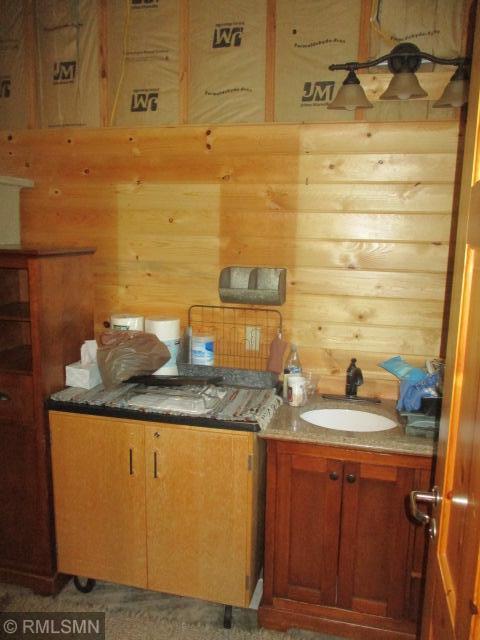 kitchen with a sink, wooden walls, and brown cabinets