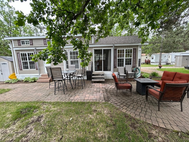 view of patio with entry steps, outdoor lounge area, a storage unit, and a sunroom