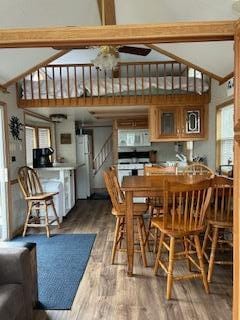 dining area with beam ceiling, wood finished floors, ceiling fan, and high vaulted ceiling