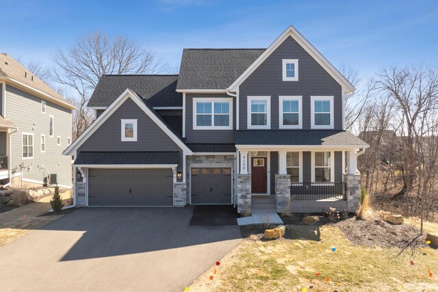 4126 Marsh Dr NE, Prior Lake, MN 55372 - craftsman-style house with covered porch, asphalt driveway, an attached garage, a shingled roof, and stone siding