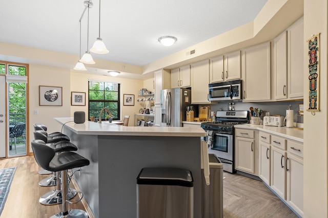 2565 Franklin Ave Unit 211, Saint Paul, MN 55114 - kitchen with stainless steel appliances, a kitchen bar, light countertops, pendant lighting, and a center island