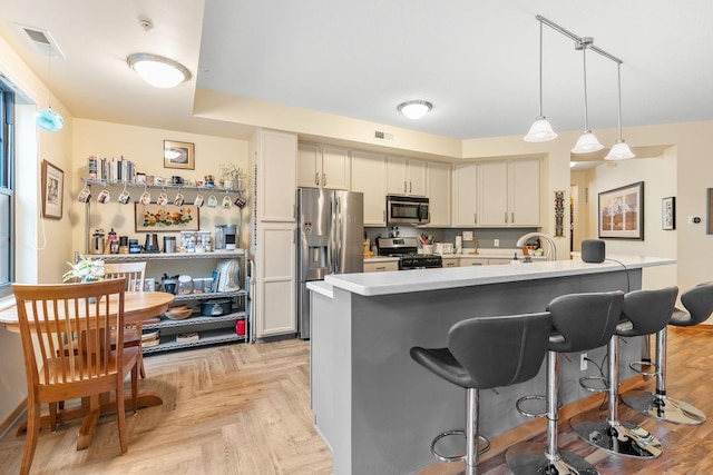 2565 Franklin Ave Unit 211, Saint Paul, MN 55114 - kitchen with appliances with stainless steel finishes, a breakfast bar area, light countertops, hanging light fixtures, and an island with sink