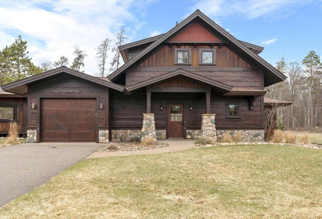 craftsman-style house featuring asphalt driveway, an attached garage, and a front lawn