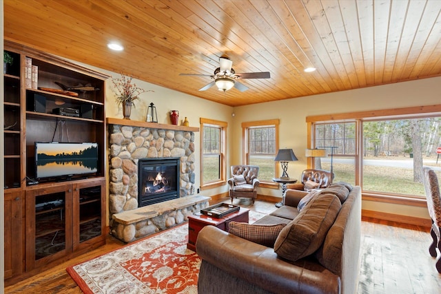 living area with wooden ceiling, a stone fireplace, recessed lighting, wood finished floors, and a ceiling fan