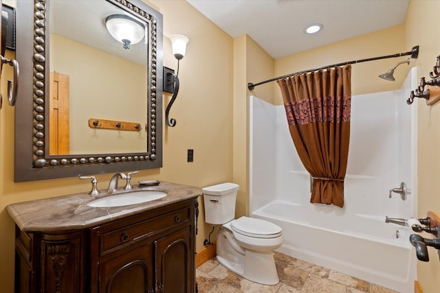 full bath featuring toilet, stone tile flooring, shower / bath combo with shower curtain, vanity, and baseboards
