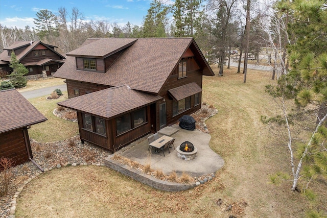 exterior space with a fire pit, roof with shingles, a sunroom, and a lawn