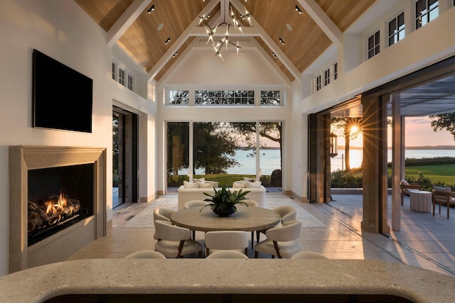 2770 Gale Rd, Woodland, MN 55391 - living area with wood ceiling with exposed beams, high vaulted ceiling, a water view, a warm lit fireplace, and a chandelier