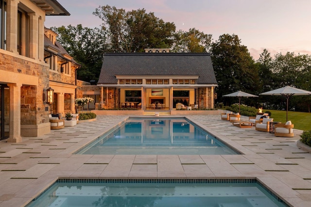 2770 Gale Rd, Woodland, MN 55391 - pool at dusk with an outdoor pool, a fireplace, and a patio