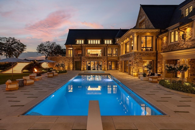 2770 Gale Rd, Woodland, MN 55391 - pool at dusk featuring a patio, a diving board, an outdoor living space, and a pool with connected hot tub